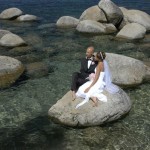 Newlyweds reflecting while sitting on a rock in the water