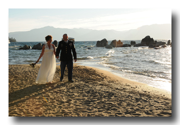 Newlyweds hold hands while walking on beach