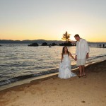 Newlyweds casually stroll the shoreline while holding hands