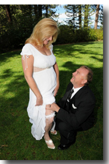 Bride displays garter as groom kneels at her side