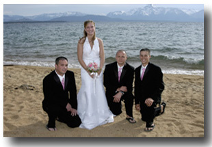 Bride standing on the beach while the groomsmen kneel